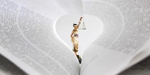justice statue viewed between the pages of a law book